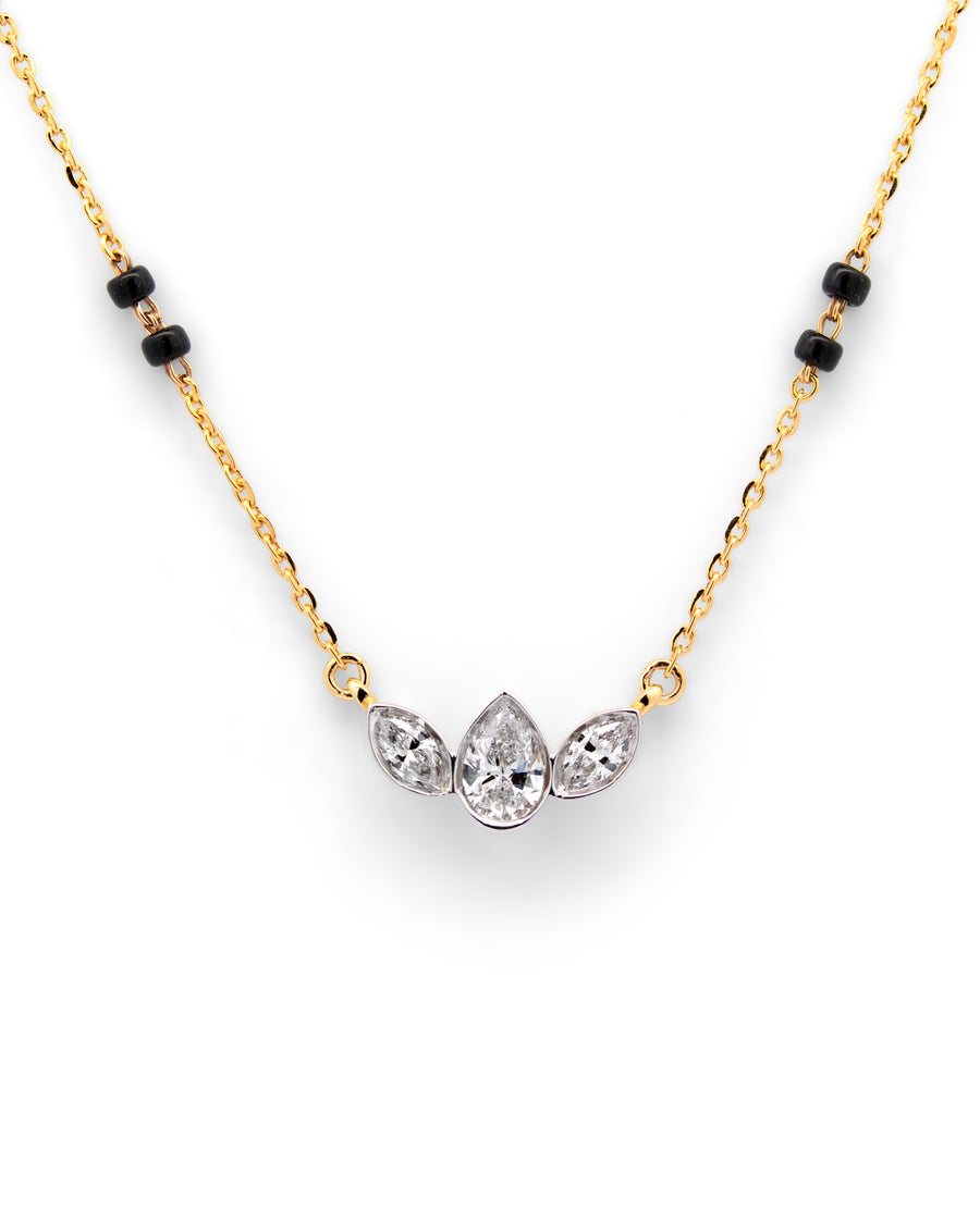 Gold necklace with black beads and three clear gemstones on a white background