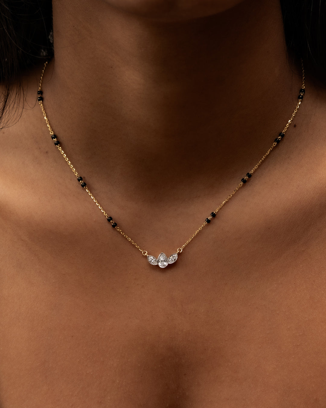 Gold necklace with black beads and clear stones on a person's neck