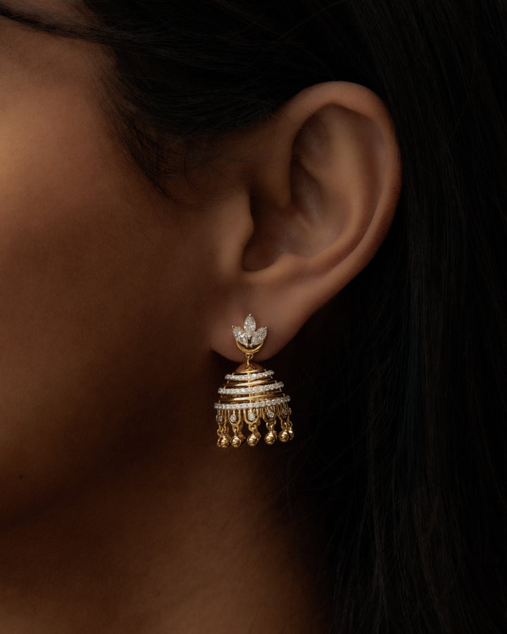 Gold earring worn by a person with a dark background