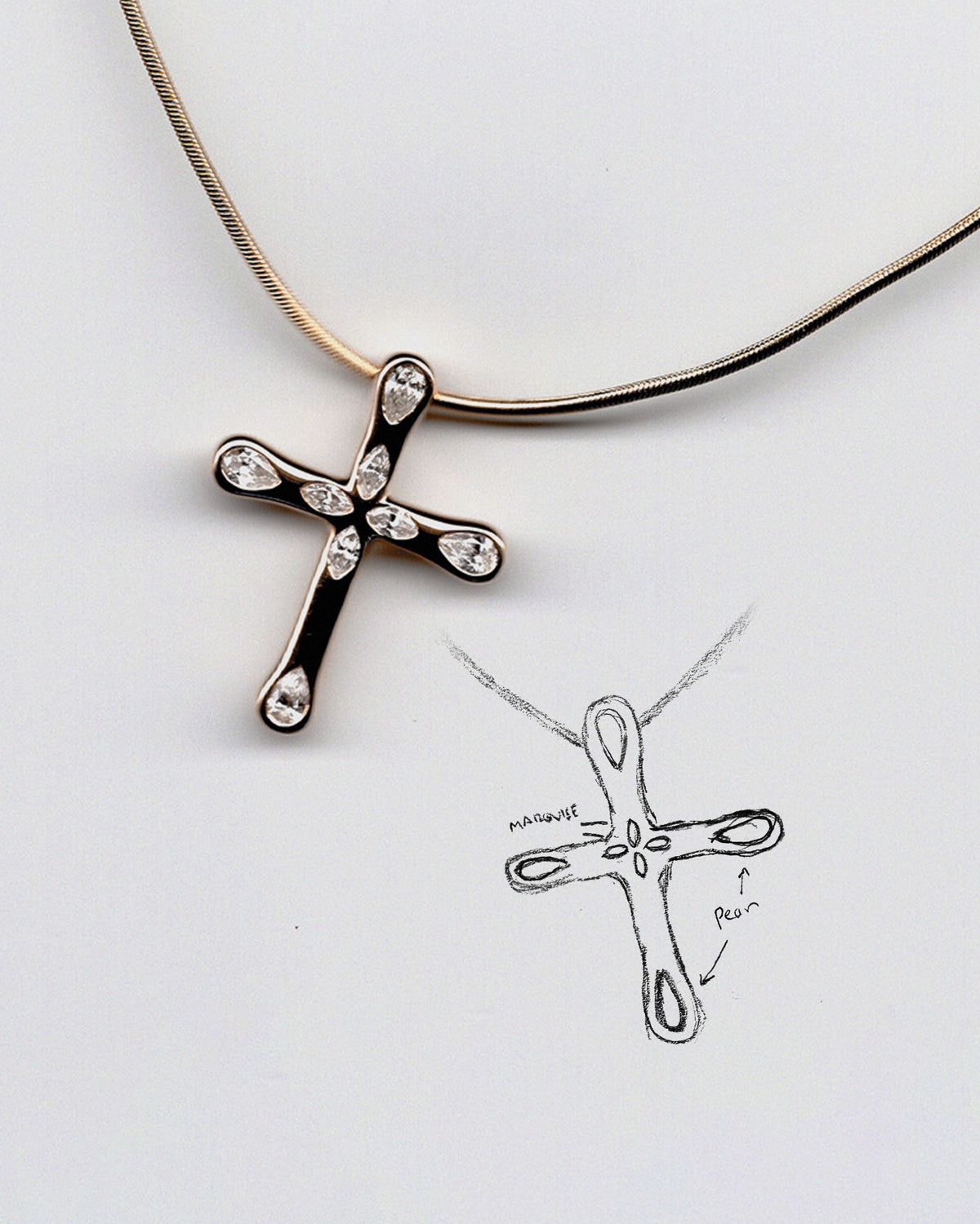 Gold cross pendant on a gold chain with a hand-drawn sketch of the same design on a white background.