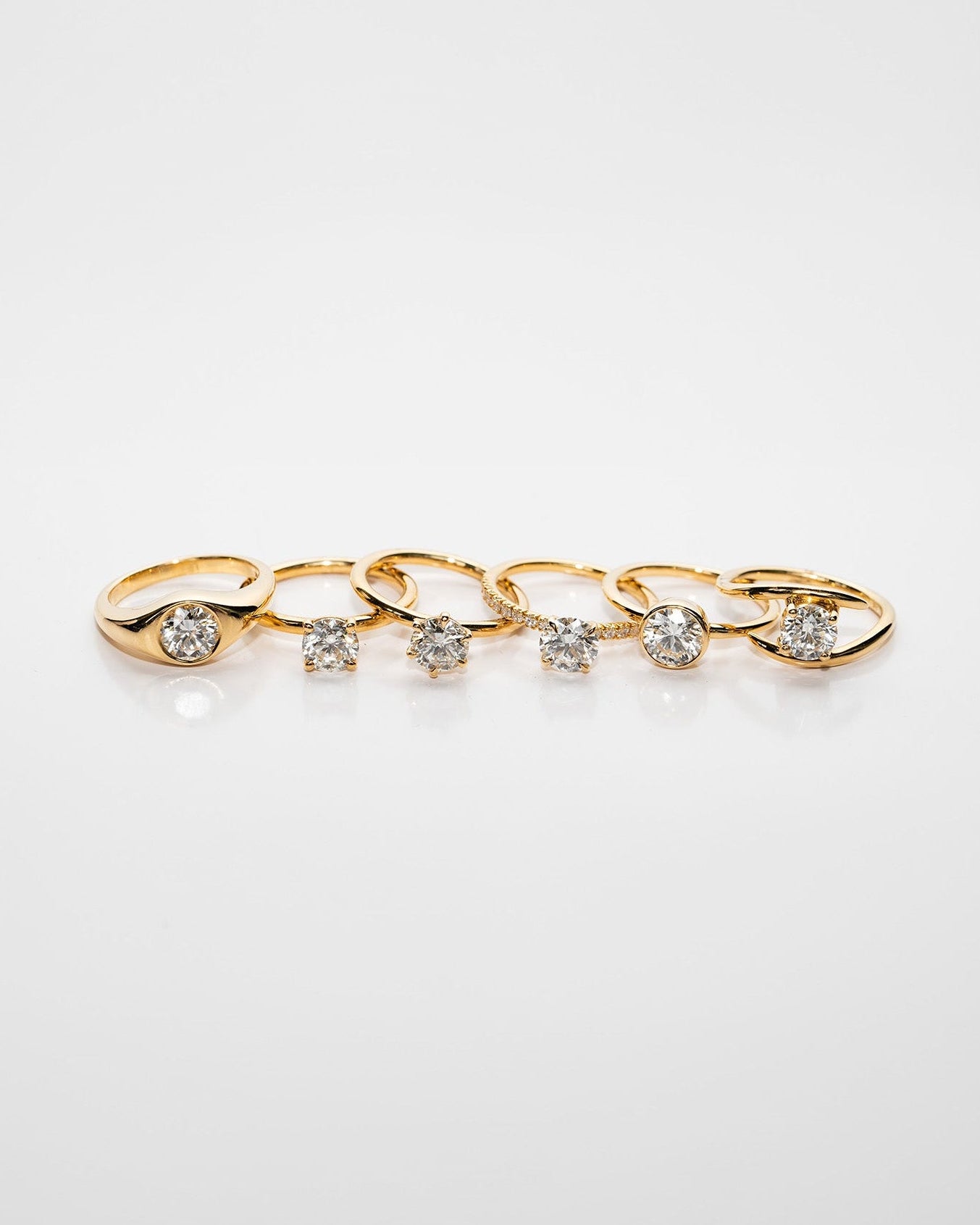 Set of gold rings with embedded diamonds on a light gray background